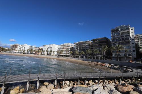 a beach with buildings and the ocean and a pier at DIFFERENTFLATS Santa Rosa in Salou