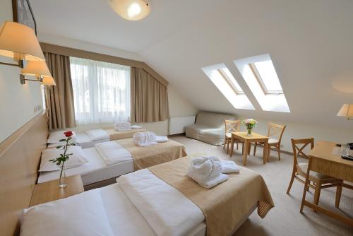 ein Hotelzimmer mit 3 Betten und einem Tisch in der Unterkunft Hotel Alpejski in Polanica-Zdrój