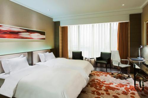 a hotel room with two beds and a desk at Crowne Plaza Nanjing Jiangning by IHG in Nanjing