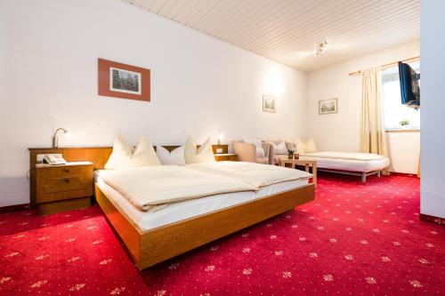 a bedroom with a large bed and a red carpet at Hotel Goldener Hirsch in Reutte