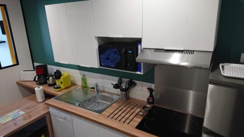 une petite cuisine avec un évier et une cuisinière dans l'établissement T3 GUYNEMER 1ER ÉTAGE Plage à 80 M Linge de lit fourni, à Les Sables-dʼOlonne