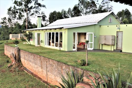 a small green house with a brick wall at Round Here Self-Catering Holiday Home in Sabie
