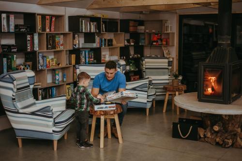 a man reading a book to a little boy at a table at Herbals - Tree&Lake houses with bath, sauna, bikes, motorboat in Mielno