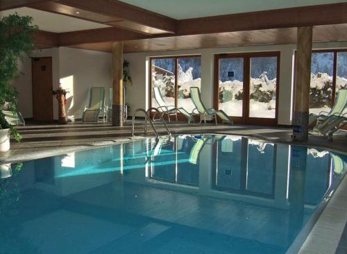 a swimming pool in a house with chairs at Hotel Kirchdach in Gschnitz