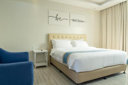 a bedroom with a large bed and a blue chair at Hampton Suites in Davao City