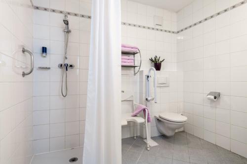 a white bathroom with a shower and a toilet at Hotel Goldener Hirsch in Reutte