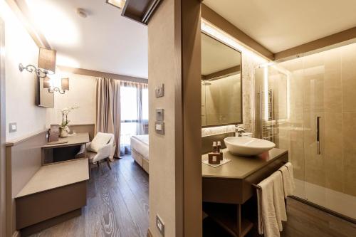 W łazience znajduje się umywalka i lustro. w obiekcie Hotel Spinale w Madonna di Campiglio