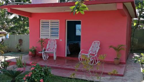 a red house with two chairs in front of it at Casa Ceno y Luisa in Viñales