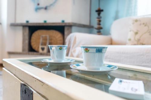 due tazze su un tavolo di vetro in soggiorno di Porto Azzurro Apartment a Varenna