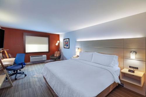 a hotel room with a large bed and a desk at Holiday Inn Express Hotel and Suites Jenks by IHG in Jenks