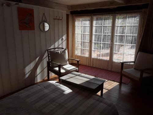 a bedroom with a bed and a chair and windows at ancienne maison des templiers in Gouillons