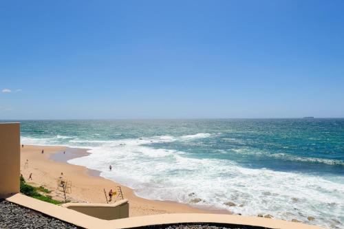 einen Strand mit Menschen, die auf dem Sand und dem Meer wandeln in der Unterkunft Bermuda 306 in Ballito