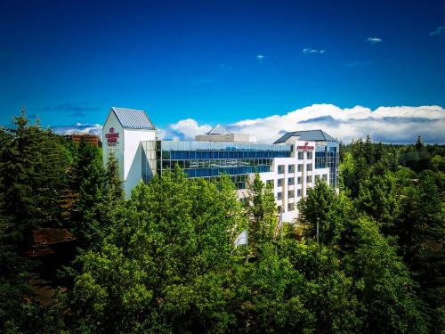 un groupe de bâtiments avec des arbres au premier plan dans l'établissement Crowne Plaza Portland - Lake Oswego, an IHG Hotel, à Lake Oswego