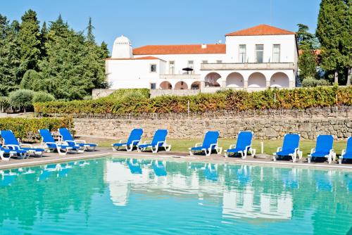 a row of blue lounge chairs next to a swimming pool at Lam Hotel Convento do Desagravo in Oliveira do Hospital