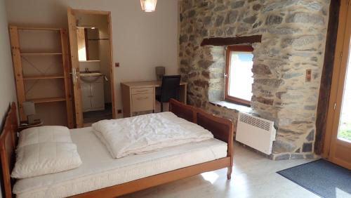 1 dormitorio con cama y pared de piedra en Gîtes Le Paradoxe des Pyrénées en Montferrier