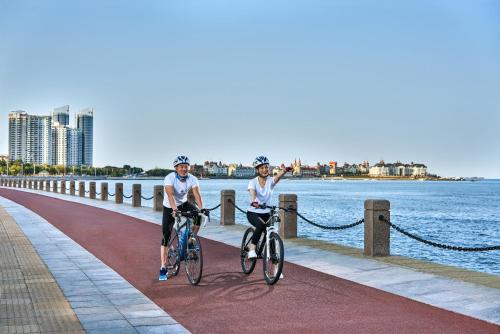 two people riding bikes on a pier next to the water at Crowne Plaza Yantai Sea View by IHG in Yantai