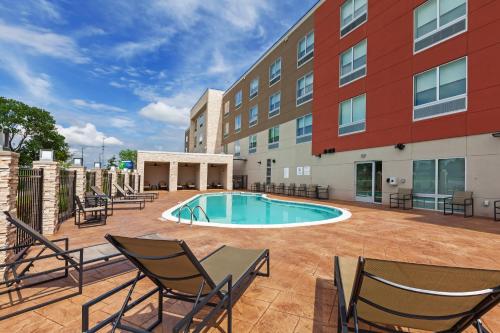 a patio with chairs and a pool in front of a building at Holiday Inn Express & Suites Tulsa South - Woodland Hills by IHG in Tulsa