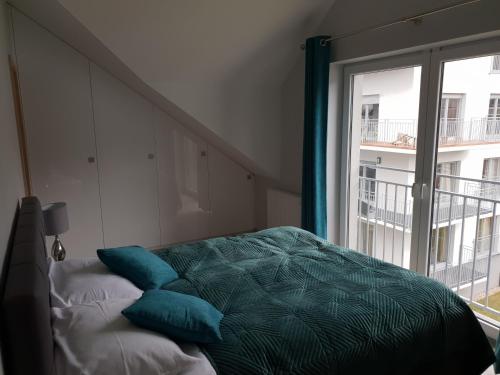łóżko z niebieskimi poduszkami w pokoju z oknem w obiekcie Vera Apartment Świeradów-Zdrój Zakopiańska 22 C m10 w Świeradowie Zdroju