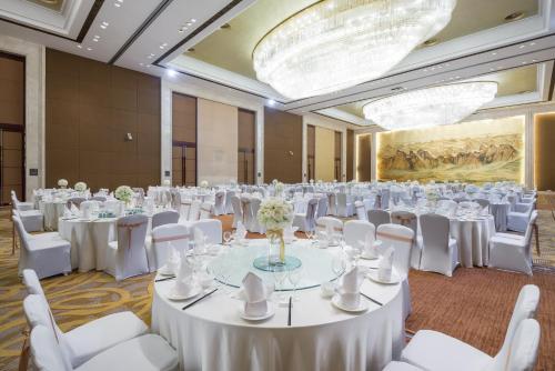 a large banquet hall with white tables and white chairs at Crowne Plaza Yichang by IHG in Yichang