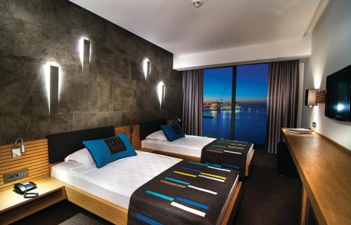 a hotel room with two beds and a large window at Ilayda Avantgarde Hotel in Kusadası