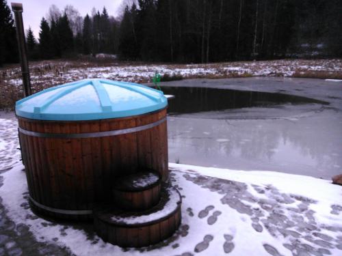 a wooden barrel in the snow next to a pond at Vana-Laane Puhkemaja in Otepää