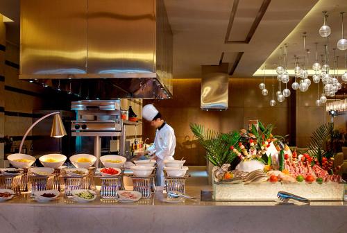 a chef preparing food in a restaurant kitchen at Expo Center Hotel - Free Shuttle Bus & Late Check-out in Yiwu