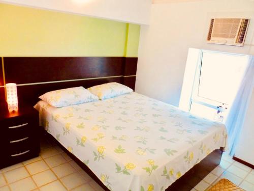 a small bedroom with a bed with a floral bedspread at Excelente Loft Ancorar in Porto De Galinhas