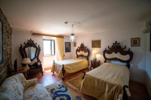 Quinta da Veiga في Covas do Douro: غرفة نوم بسريرين واريكة فيها