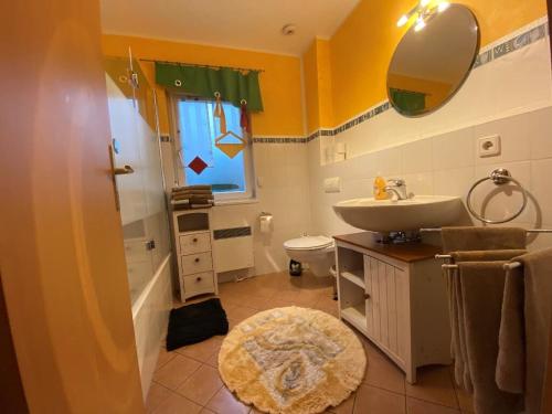 a bathroom with a sink and a toilet and a mirror at Reiger Ferienwohnungen in Wackersdorf