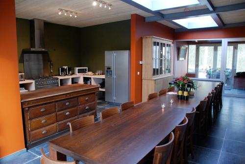 uma grande cozinha com uma longa mesa de madeira e cadeiras em Jachthuis Au Bois Du Gheer em Le Gheer