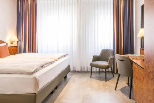 Un dormitorio con una cama, un escritorio y una silla. en BARDOLINO Fine.Food.Hotel, en Núremberg