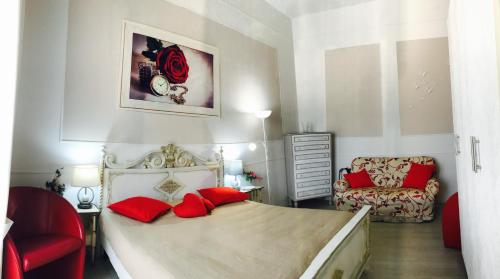Casa di Alice Luxury Hospitality - Elevator, Fast WiFi في سيراكوزا: غرفة نوم بسرير ومخدات حمراء وكرسي