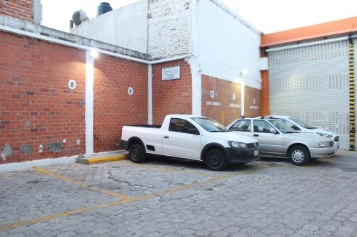 two cars parked in a parking lot next to a brick building at Hotel Plaza Aleman in León