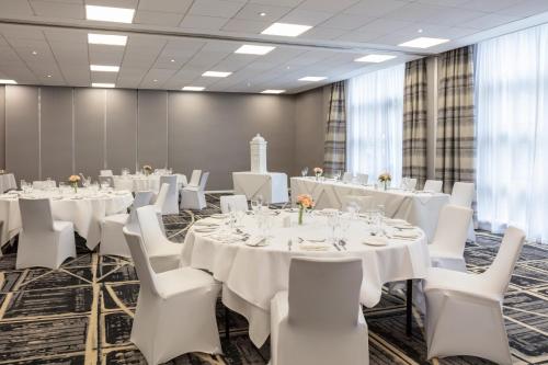 a conference room with white tables and white chairs at Novotel Newcastle Airport in Newcastle upon Tyne