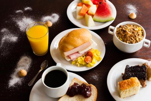 a table topped with plates of breakfast foods and drinks at Hotel Holiday Foz in Foz do Iguaçu