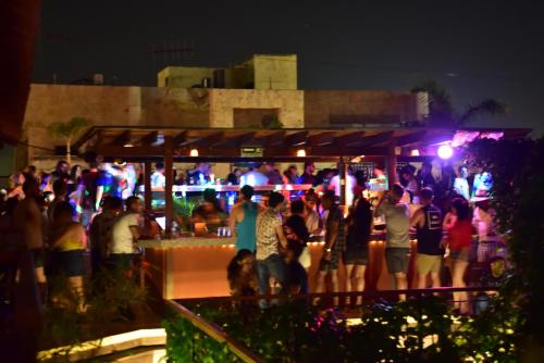 a crowd of people standing around a bar at night at La Brisa Loca Hostel in Santa Marta