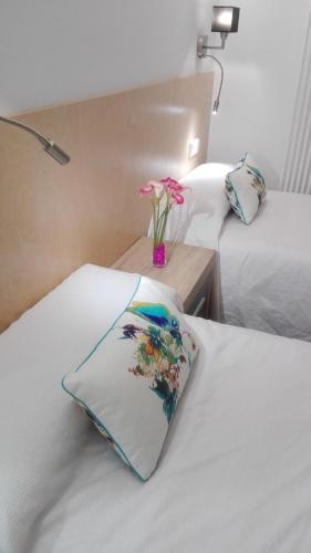 a hotel room with two beds and a vase with flowers at Apartamentos Turísticos Los Picos in Liérganes