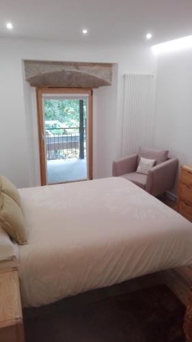 a bedroom with a bed and a chair and a window at Apartamentos Turísticos Los Picos in Liérganes