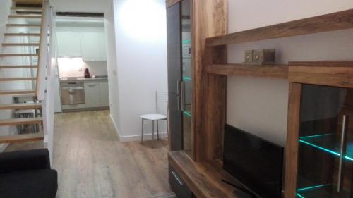 a living room with a flat screen tv and a staircase at Apartamentos Turísticos Los Picos in Liérganes