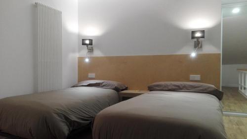 two beds in a room with lights on the wall at Apartamentos Turísticos Los Picos in Liérganes