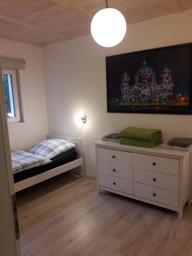 ein Schlafzimmer mit einem Bett und einer Kommode in der Unterkunft Cottage am Wald bei Berlin in Falkensee