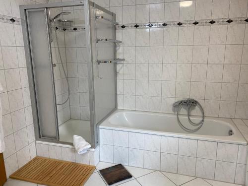 a white tiled bathroom with a shower and a tub at Privatquartier im Ortskern von Westerstede in Westerstede