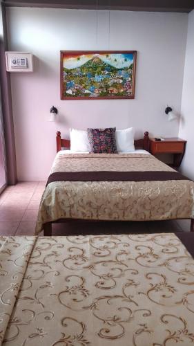 a bedroom with a bed and a painting on the wall at Hotel Las Colinas in Fortuna