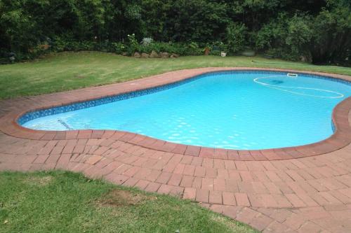 a swimming pool with a brick walkway around it at Clarens Socialites Garden Apartment #2 in Bethlehem