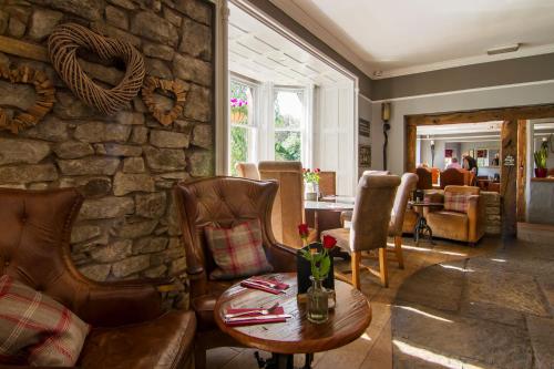 un soggiorno con parete in pietra, tavolo e sedie. di Romneys Apartments & Suites a Kendal