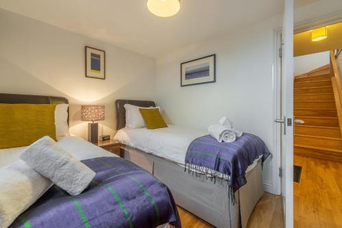 een slaapkamer met 2 bedden met paarse lakens en een deur bij Copperhouse View in Hayle