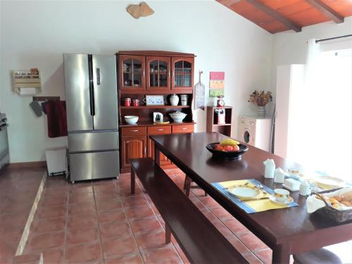 a kitchen with a table and a stainless steel refrigerator at Casa Branca do Moinho in Salgueiro