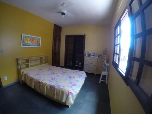 a bedroom with a bed and a yellow wall at Paraíso Casa de Praia em Saquarema in Saquarema