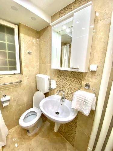 a bathroom with a toilet and a sink and a mirror at Glorious Rooms in Niš