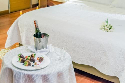a bottle of champagne and a plate of food on a bed at Bogota Plaza Hotel in Bogotá